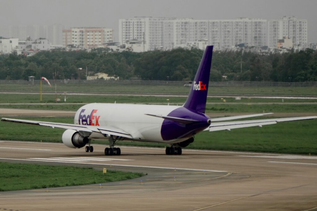 FedEx cargo plane on the runway, preparing for departure with cityscape in the background.